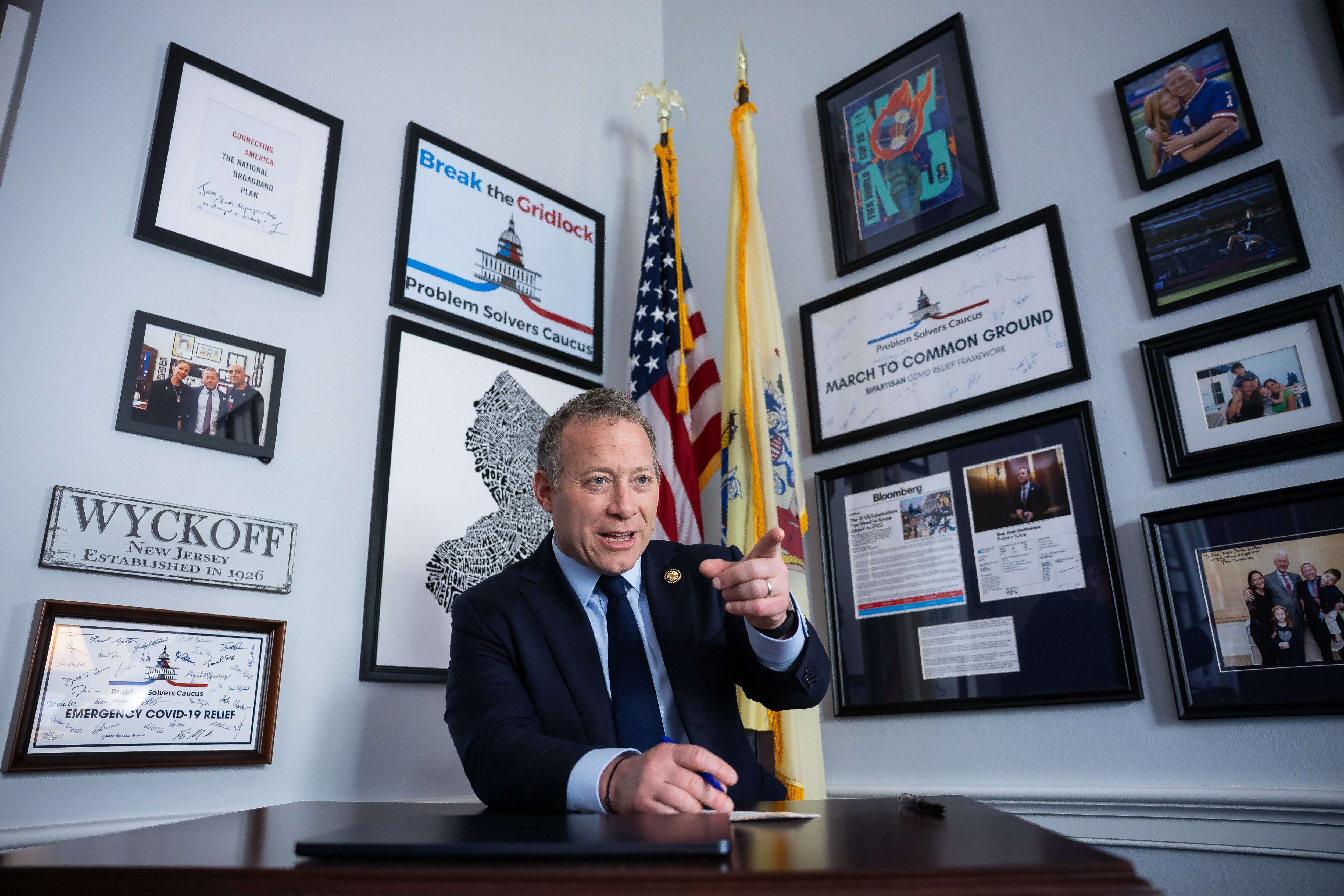 Gottheimer speaks with an aide in his office on Capitol Hill, with Problem Solvers Caucus artwork hanging on the walls behind him.