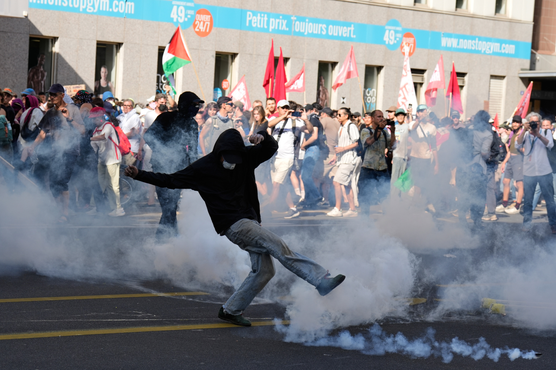 A protester kicks a canister during a "No G7" demonstration in Geneva, Switzerland, Sunday, June 14, 2026, ahead of the G7 summit scheduled to take place June 15-17. (AP Photo/Baz Ratner)