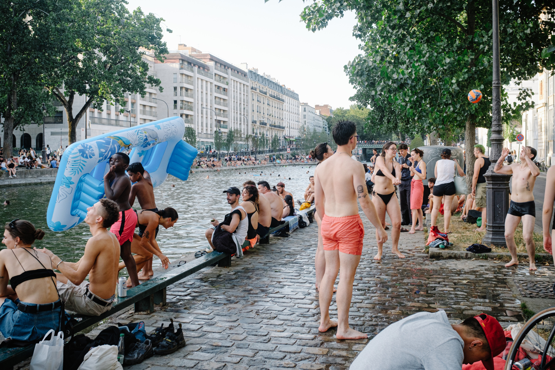 Young people relax, play volleyball, and swim with an inflatable mattress on the banks of the Canal Saint-Martin in Paris, France, on June 23, 2026, as the capital experiences an intense heatwave that has lasted for several days. (Photo by Samuel Boivin/NurPhoto via Getty Images)