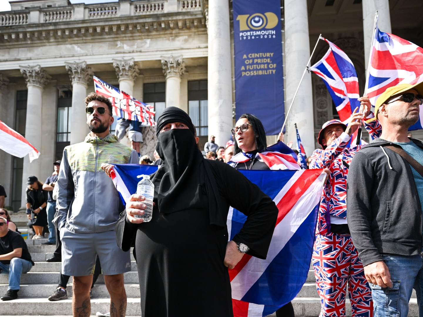 PORTSMOUTH, ENGLAND - SEPTEMBER 12: An anti-migrant protester wears a burkha during an anti-migrant march through the city to Guildhall, on September 12, 2026 in Portsmouth, England. A volunteer RNLI crew rescued approximately 140 migrants from a "mega dinghy" crossing the English Channel last Sunday night, triggering intense far-right protests and road blockades in Eastney, Portsmouth. Stand Up To Racism are staging a counter protest to today's far right march by the self-styled South Coast Patriots. (Photo by Finnbarr Webster/Getty Images)